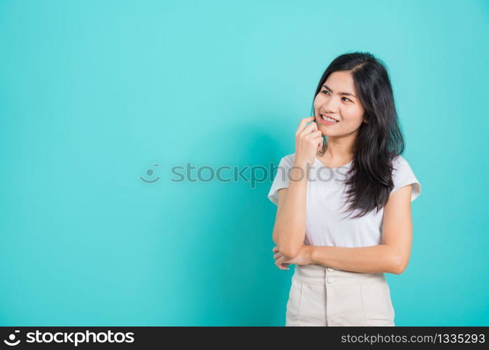 Portrait Asian beautiful happy young woman smile white teeth wear white t-shirt standing relaxed thinking about something about the question, on a blue background with copy space