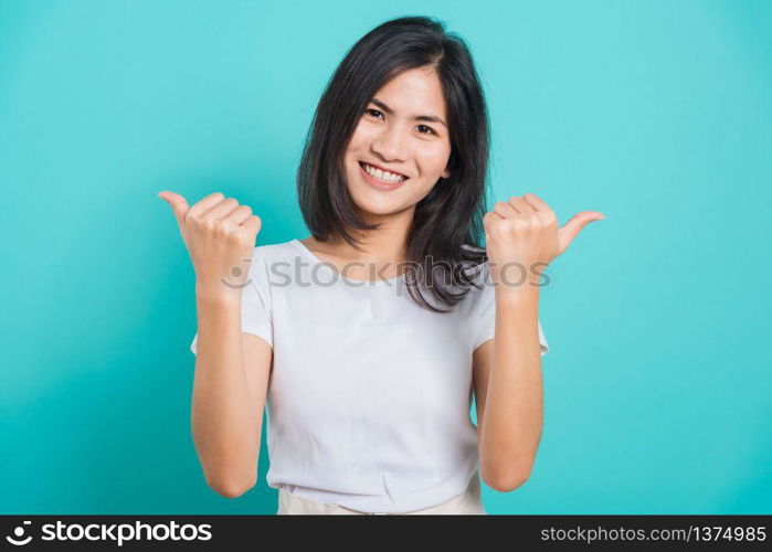 Portrait Asian beautiful happy young woman smile white teeth wear white t-shirt standing successful woman giving two thumbs up gesture, on a blue background with copy space