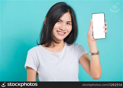 Portrait Asian beautiful happy young woman standing smile showing blank screen mobile phone looking to camera, shoot the photo in a studio on a blue background, There was copy space