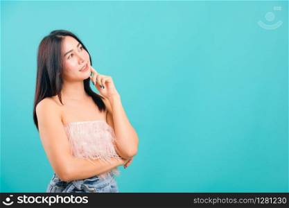 Portrait asian beautiful woman smiling her standing thinking looking out on blue background, with copy space for text
