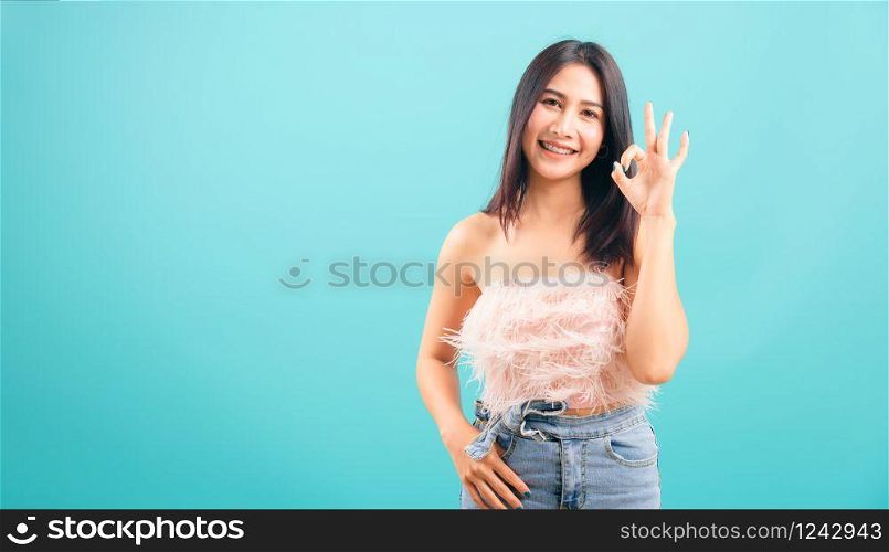 Portrait asian beautiful woman smiling showing hand okay sign her looking to camera on blue background, with copy space for text