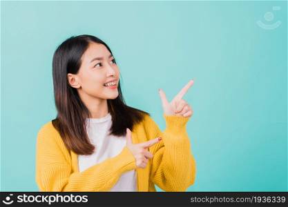 Portrait Asian beautiful young happy woman teen smiling show white teeth she&rsquo;s pointing finger up to side empty space studio shot isolated on blue background, Dental health concept