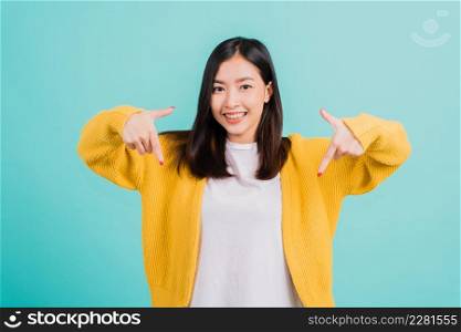 Portrait Asian beautiful young happy woman teen smiling show white teeth she&rsquo;s pointing finger down to empty space studio shot isolated on blue background, Dental health concept