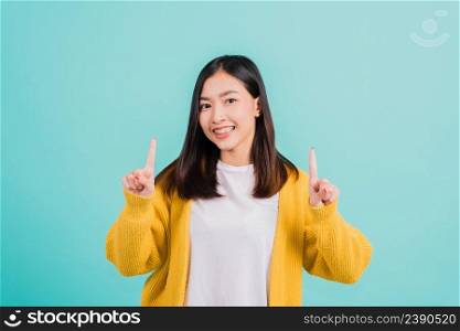 Portrait Asian beautiful young happy woman teen smiling show white teeth she’s pointing finger up to empty space studio shot isolated on blue background, Dental health concept