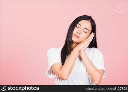 Portrait Asian beautiful young woman pretended emotions sleeping tired eyes closed dreaming with hands together near face, studio shot on pink background, with copy space, insomnia concept
