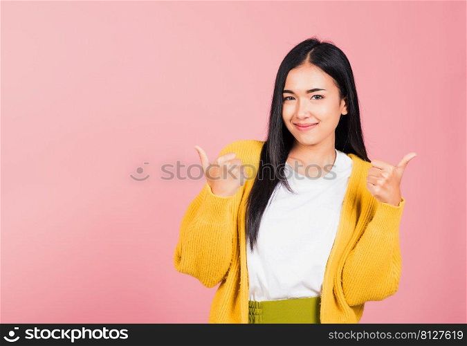 Portrait Asian beautiful young woman smile she standing made finger thumbs up, Ok sign to agree studio shot isolated on pink background, Thai female successful like finger gesture with copy space