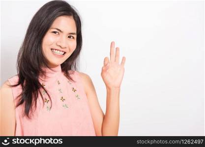 Portrait Asian beautiful young woman standing, She made finger OK symbol sign to agree and looking at camera, shoot photo in studio on white background, There was copy space
