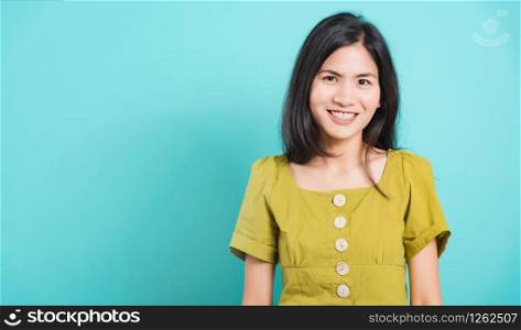 Portrait Asian beautiful young woman standing smile seeing white teeth, She looking at the camera, shoot photo in studio on blue background. There was a copy space to put text on the left-hand side.