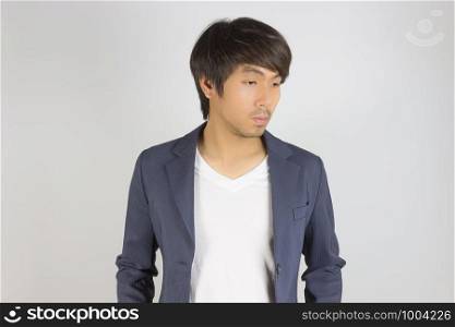 Portrait Asian Casual Businessman in Navy Blue Suit with T-Shirt Look Below on Grey Background. Casual businessman wear suit fashion in semi formal style