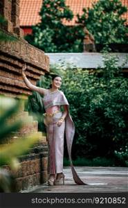 Portrait Asian charming woman wearing beautiful typical Thai dress identity culture of Thailand in ancient temple or famous place with gracefully pose, copy space
