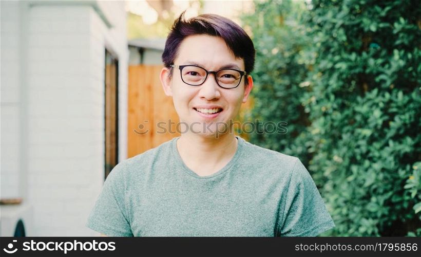 Portrait Asian Chinese man feeling happy smiling at house. Young friendly male relax toothy smile looking to camera while standing in the garden at home in the morning concept.
