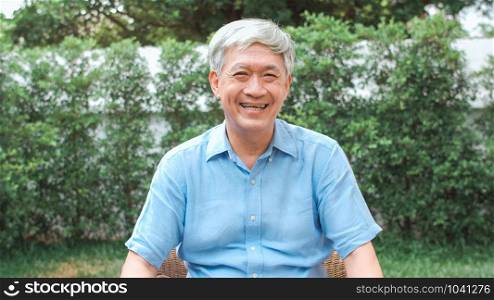 Portrait Asian Chinese senior man feeling happy smiling at home. Older male relax toothy smile looking to camera while lying in the garden at home in the morning concept.