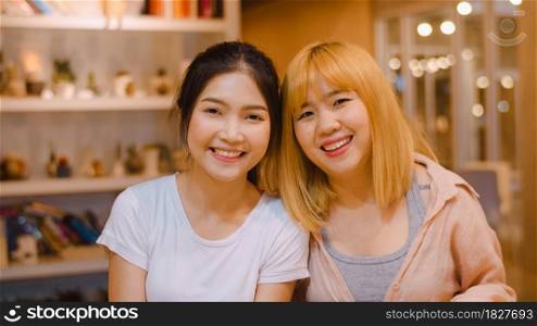 Portrait Asian Chinese women feeling happy smiling in library at university. Young undergraduate friends girl relax toothy smile looking to camera at college campus overtime at night concept.