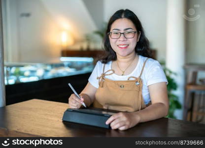 Portrait asian freelance people business female wearing glasses stylish hipste Draw or taking note on digital tablet with electronic pen for browsing internet, chatting and blogging in coffee shop.