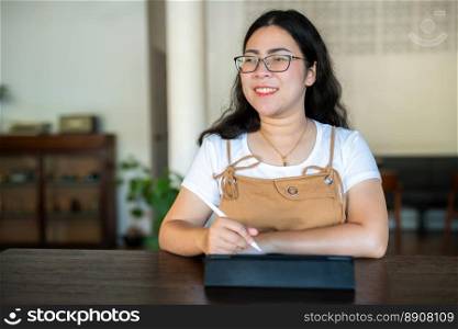 Portrait asian freelance people business female wearing glasses stylish hipste Draw or taking note on digital tablet with electronic pen for browsing internet, chatting and blogging in coffee shop.