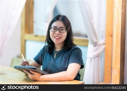 Portrait asian freelance people business female wearing glasses stylish hipster Draw or taking note on digital tablet with electronic pen for browsing internet, chatting and blogging in coffee shop.