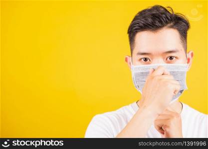 Portrait Asian handsome young man wearing face mask protective against coronavirus or COVID-19 virus showing demonstrating correct step, studio shot isolated yellow background