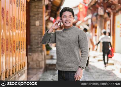 Portrait asian happiness man using smart mobile phone for calling when travelling over the Lijiang old town, China, travel and tourism with friendship, lifestyle and leisure concept