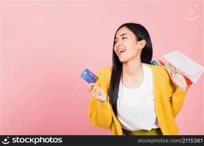 Portrait Asian happy beautiful young woman shopper smiling standing excited holding online shopping bags colorful and credit card for payment on hand in summer, studio shot isolated on pink background