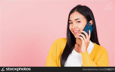 Portrait Asian happy beautiful young woman smile talking by smartphone looking to camera isolated, studio shot isolated on pink background, Thai female hold the phone to calling with copy space