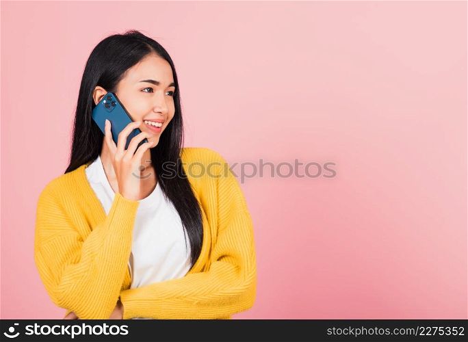 Portrait Asian happy beautiful young woman smile talking by smartphone looking to side away isolated, studio shot isolated on pink background, Thai female hold the phone to calling with copy space