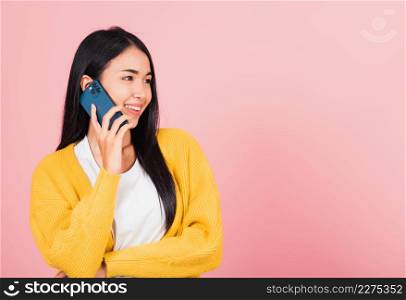 Portrait Asian happy beautiful young woman smile talking by smartphone looking to side away isolated, studio shot isolated on pink background, Thai female hold the phone to calling with copy space