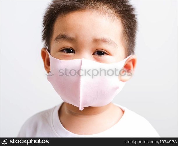 Portrait Asian little child boy wearing cloth face mask protective filter dust pm2.5, COVID-19 or coronavirus concept he looking to camera, studio shot isolated on white background with copy space