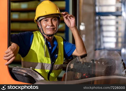 Portrait asian male warehouse worker using forklift truckin large warehouse distribution center. Business warehouse storage transportation and logistic concept