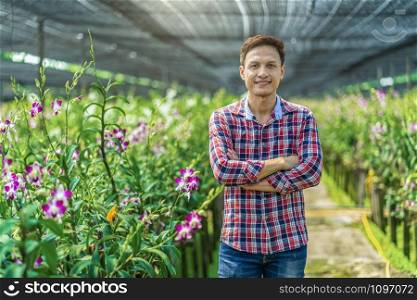 Portrait asian small business owner of orchid gardening farm, The purple orchids are blooming in the garden farm, Happiness founder are arms crossed, Purple orchids in farming of bangkok, thailand.