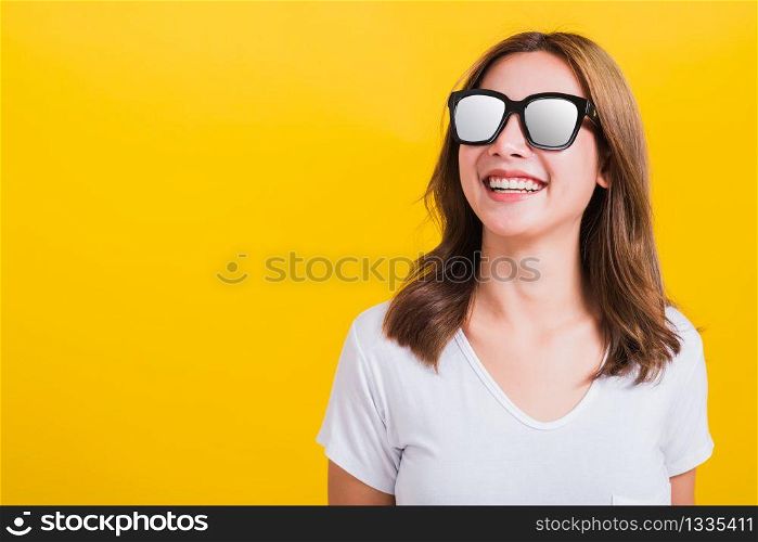 Portrait Asian Thai beautiful young woman happy smiling white teeth with sunglasses and looking side space, studio shot isolated on yellow background, with copy space