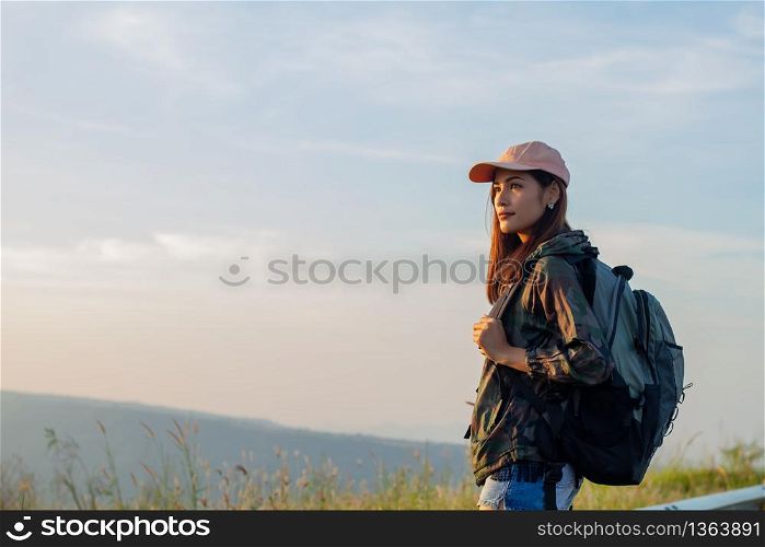 Portrait Asian woman backpacking. She was smiling and happy to travel at sunrise seaside mountain peak
