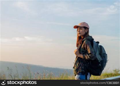 Portrait Asian woman backpacking. She was smiling and happy to travel at sunrise seaside mountain peak