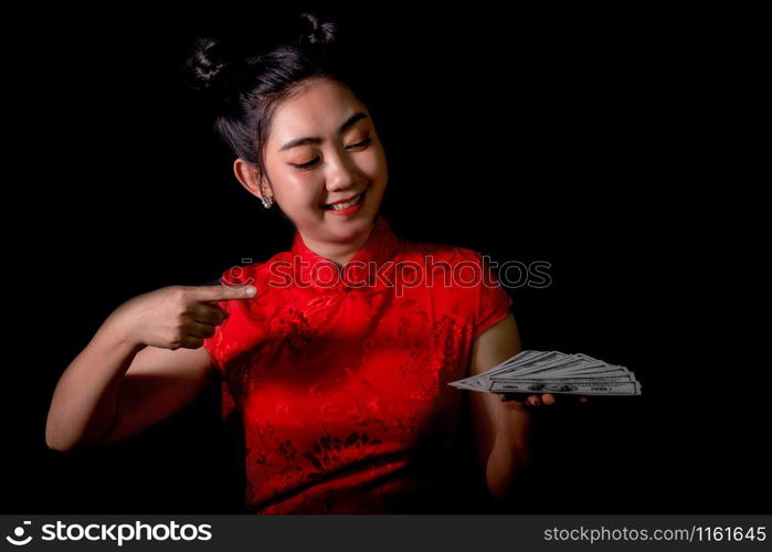 Portrait Asian woman red dress traditional cheongsam holding Money 100 Us dollar bills at black background, China Girl, Concept Chinese New Year