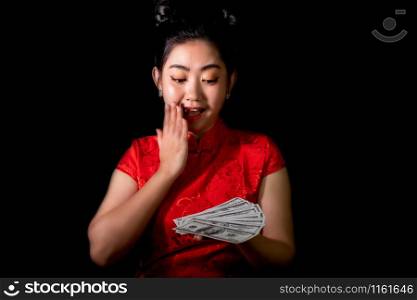 Portrait Asian woman red dress traditional cheongsam holding Money 100 Us dollar bills at black background, China Girl, Concept Chinese New Year