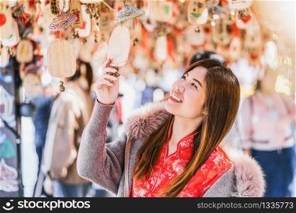 Portrait asian woman traveler looking the amulet with bell with china language in lijiang old town, yunnan, China, travel and tourist, culture and traditional concept