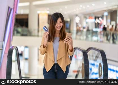 Portrait Asian woman using credit card with smart mobile phone for online shopping in department store, technology money wallet and online payment concept, credit card mockup