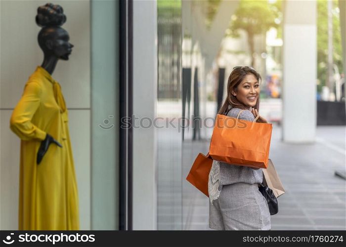 Portrait Asian woman walking and shopping beside of store shop with happy action at department center, lifestyle fashion and leisure, sales and black friday concept
