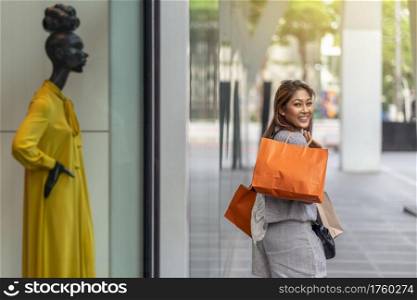 Portrait Asian woman walking and shopping beside of store shop with happy action at department center, lifestyle fashion and leisure, sales and black friday concept