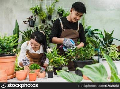 Portrait asian young gardener couple wearing apron use garden equipment and help to take care the houseplant in shop together, small business with green plant