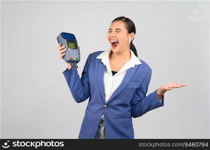 Portrait Asian young woman in officer uniform showing credit card and credit card payment machine, copy space for insert advertising your product, isolated on white background