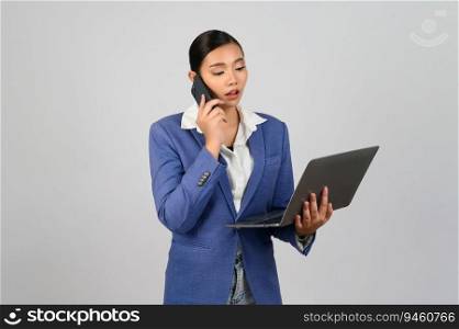 Portrait Asian young woman in officer uniform standing posture talking with mobile phone during working with laptop computer in hand,  isolated on white background
