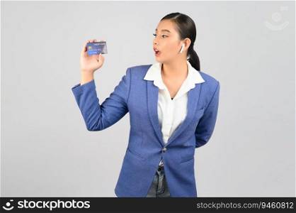 Portrait Asian young woman in officer uniform standing posture talking with wireless earphone and showing credit card in hand,  isolated on white background