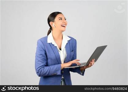 Portrait Asian young woman in officer uniform standing posture talking with wireless earphone on mobile phone during working with laptop computer in hand,  isolated on white background