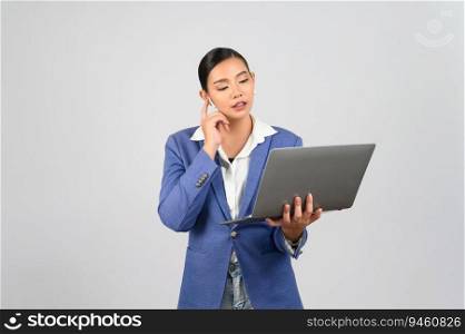 Portrait Asian young woman in officer uniform standing posture talking with wireless earphone on mobile phone during working with laptop computer in hand,  isolated on white background