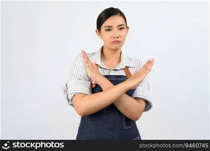 Portrait Asian young woman in waitress uniform and apron standing showing cross arms posture, Pretty woman with hand signal for feel bad or ignore isolated on white background