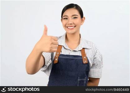 Portrait Asian young woman in waitress uniform and apron standing showing thumb up posture, Cheerful girl  happy smiling with hand signal for good, isolated on white background