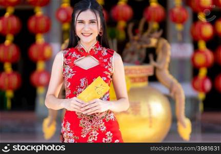 Portrait Asian young woman wearing red cheongsam dress traditional decoration holding yellow envelopes with the Chinese text Blessings written on it Is a Good luck for Chinese New Year Festival