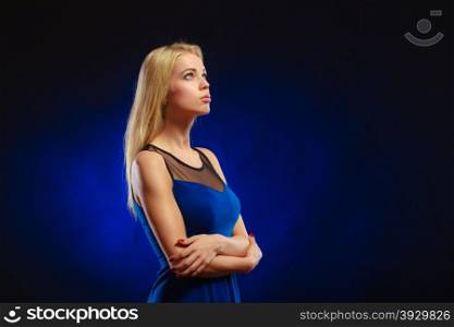 Portrait attractive thoughtful woman, blonde long hair girl in evening dress looking up dreaming, face profile dark blue background
