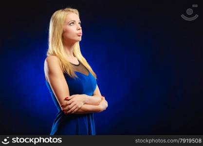 Portrait attractive thoughtful woman, blonde long hair girl in evening dress looking up dreaming, face profile dark blue background