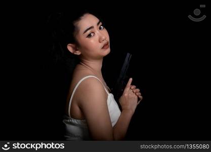 Portrait beautiful Asia woman one hand holding gun at the black background, Young sexy girl long hair with a handgun, Pretty women stand with a pistol, look at camera